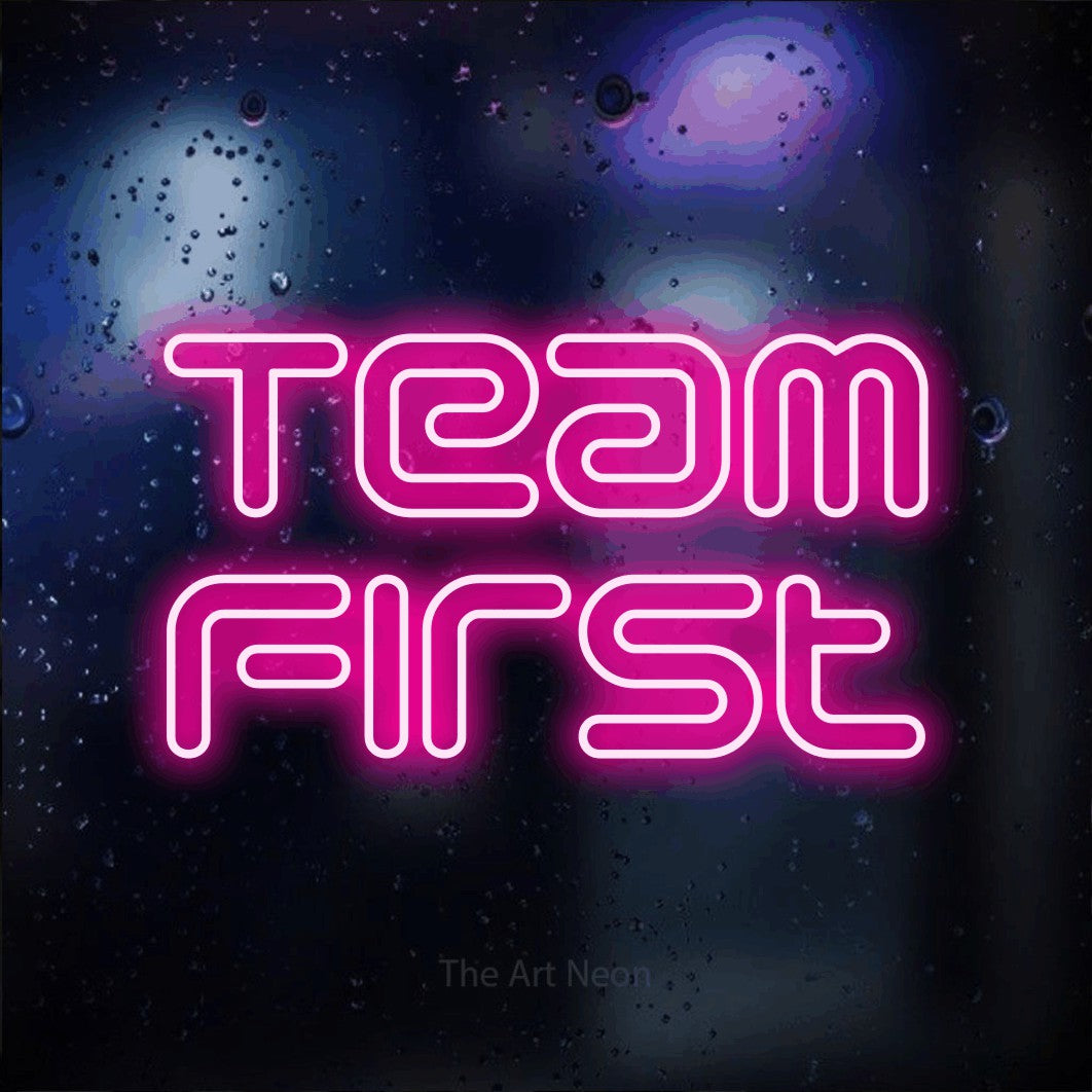 LED neon sign reading “Team First”, arranged in 2 lines.
