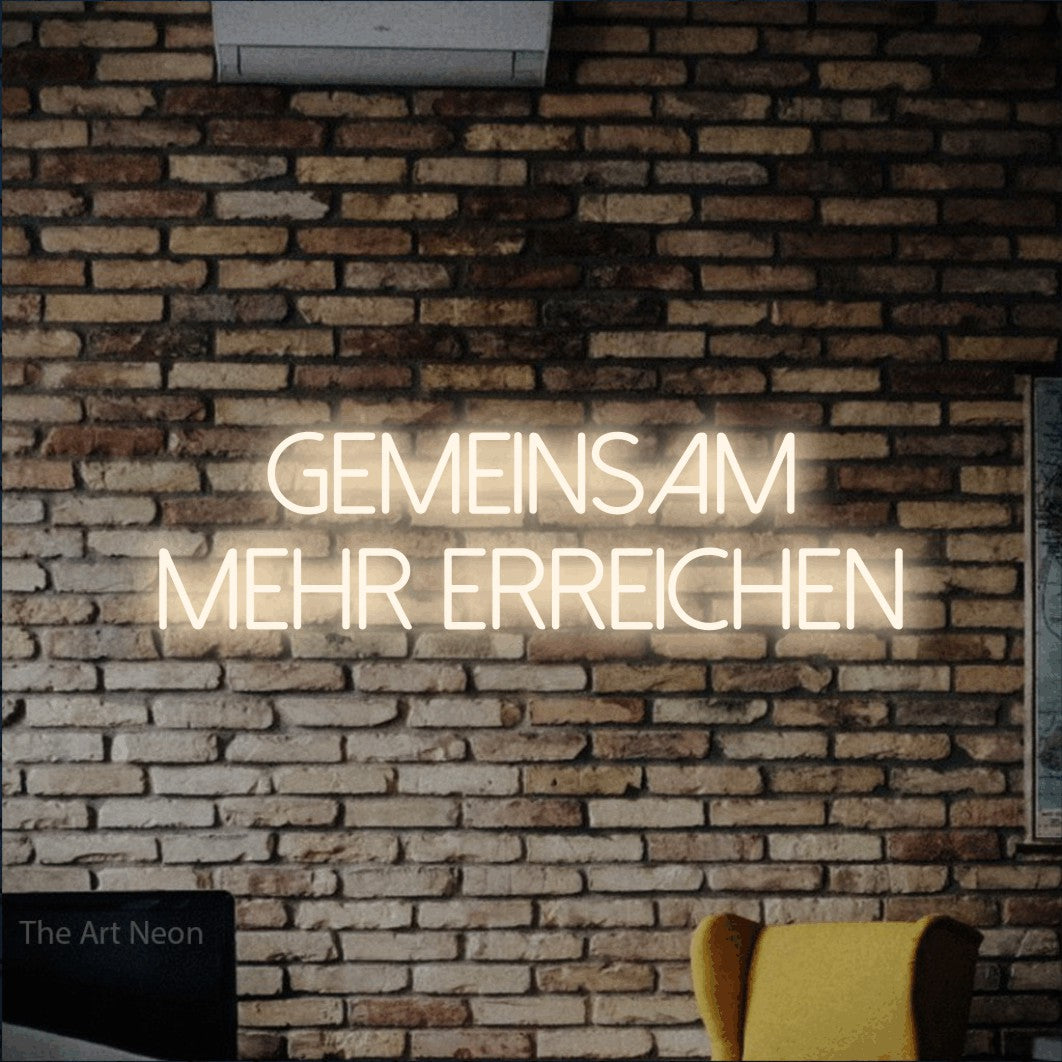 LED neon sign reading “Gemeinsam mehr erreichen”, arranged in 2 lines.