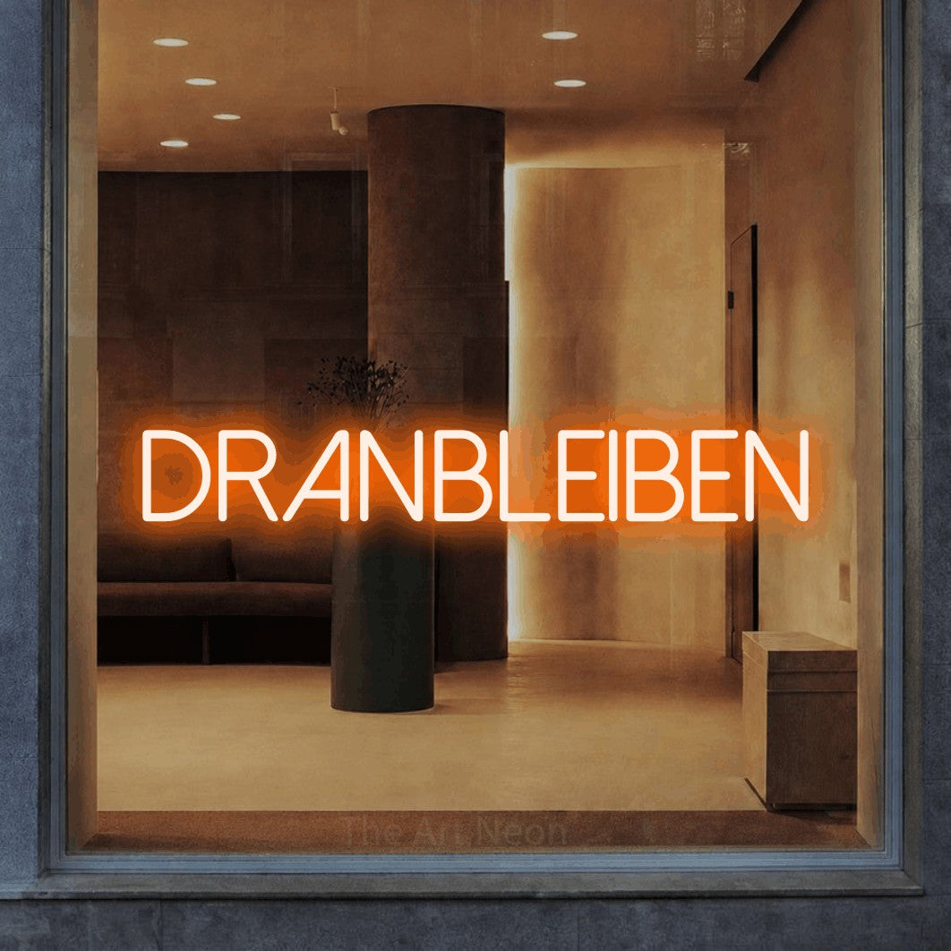 LED neon sign reading “DRANBLEIBEN”, arranged in a single line.