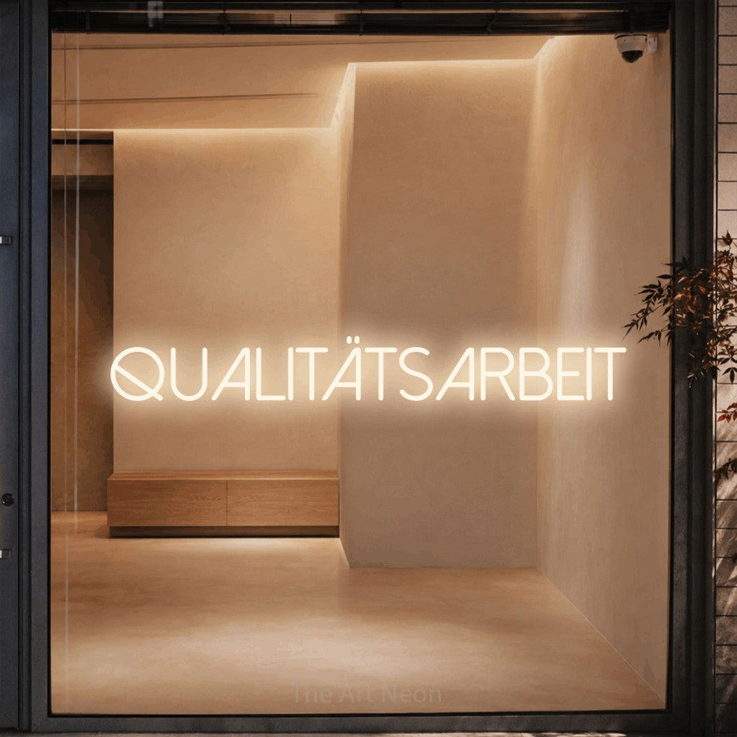LED neon sign reading “qualitätsarbeit”, arranged in a single line.