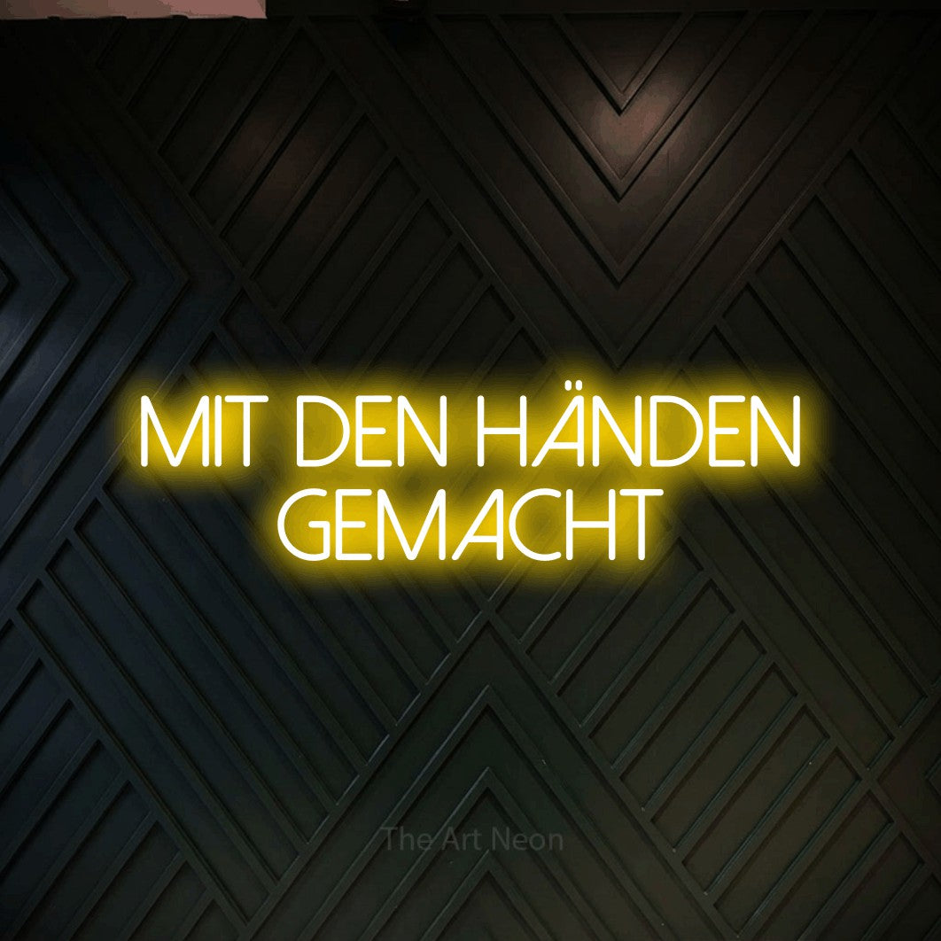 LED neon sign reading “mit den händen gemacht”, arranged in 2 lines.