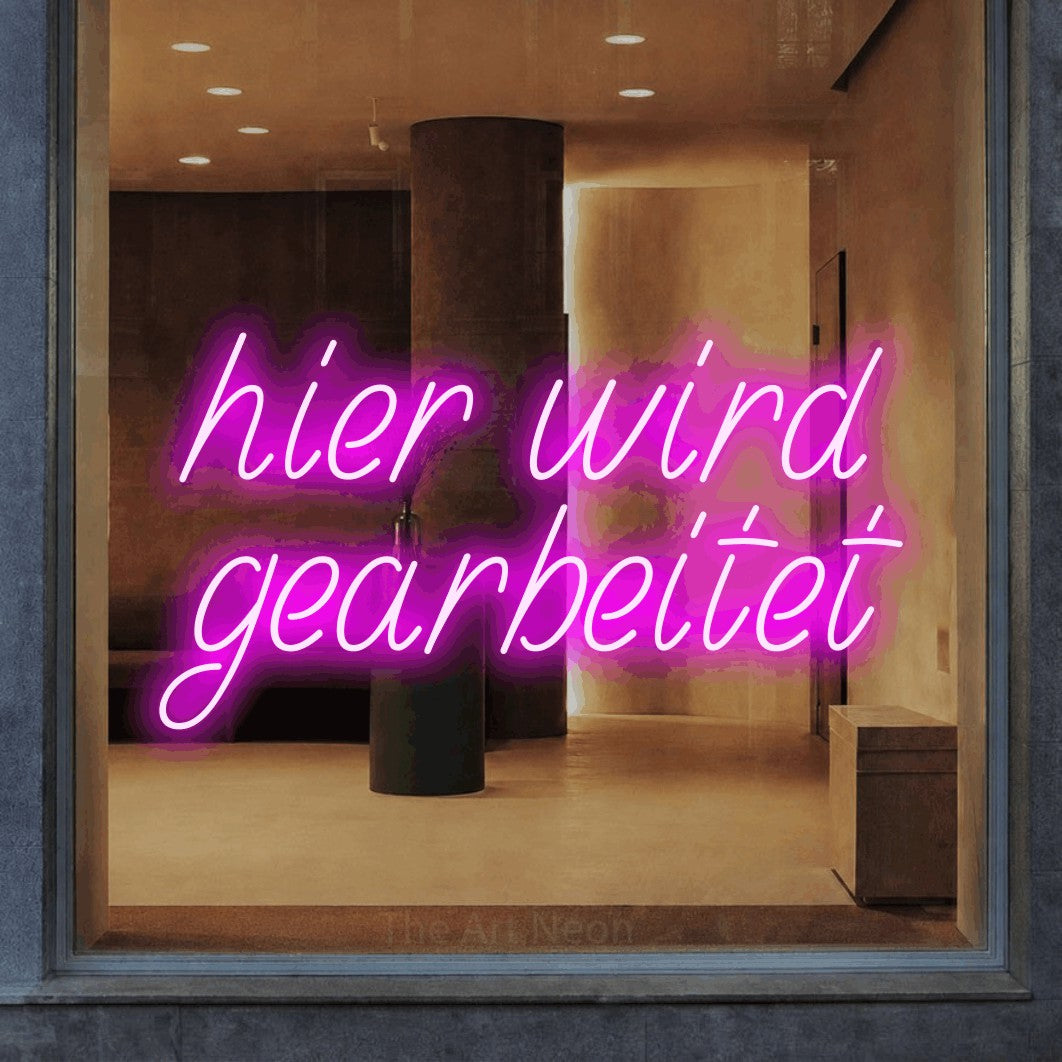 LED neon sign reading “hier wird gearbeitet”, arranged in 2 lines.