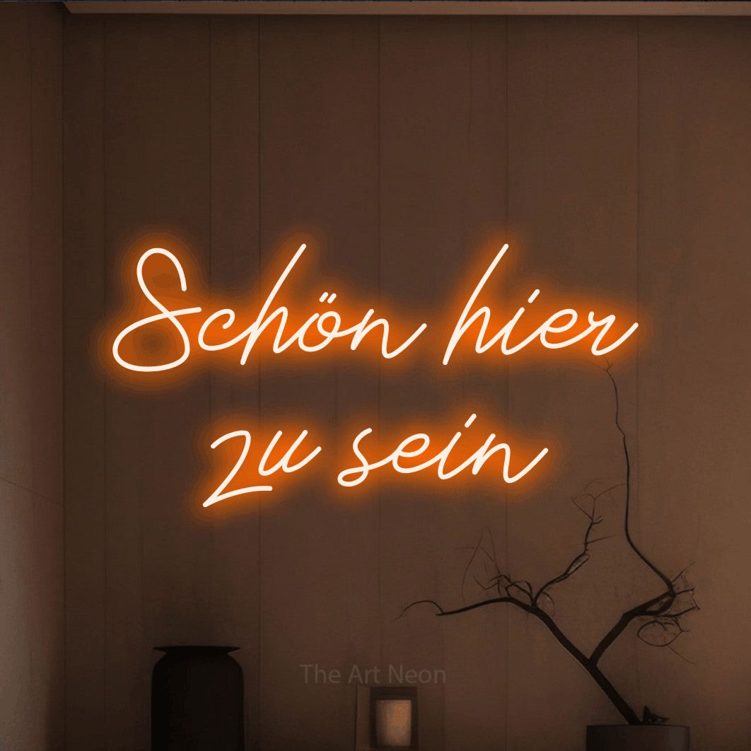 LED neon sign reading “Schön hier zu sein”, arranged in 2 lines.