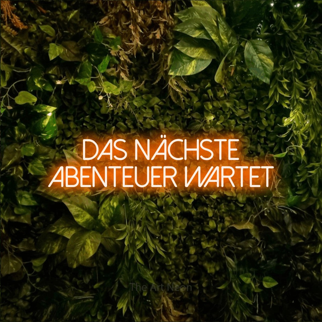 LED neon sign displaying “Das nächste Abenteuer wartet”.