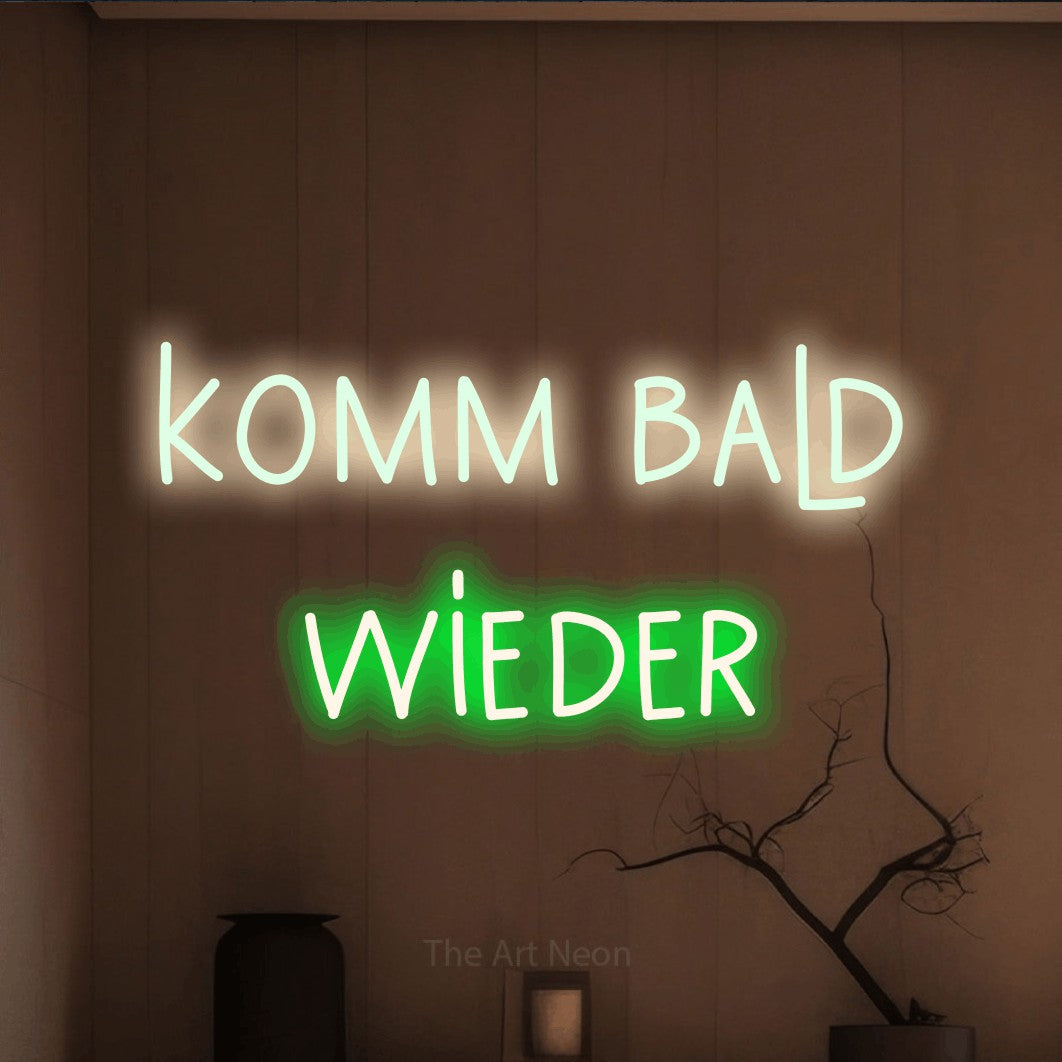 LED neon sign reading “komm bald wieder”, arranged in 2 lines.