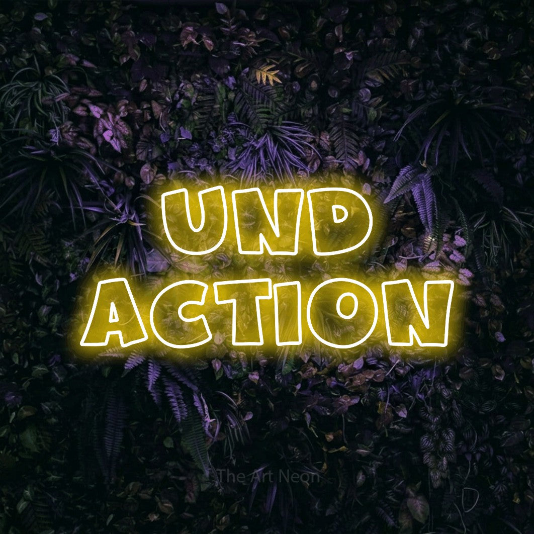 LED neon sign reading “und action”, arranged in 2 lines.