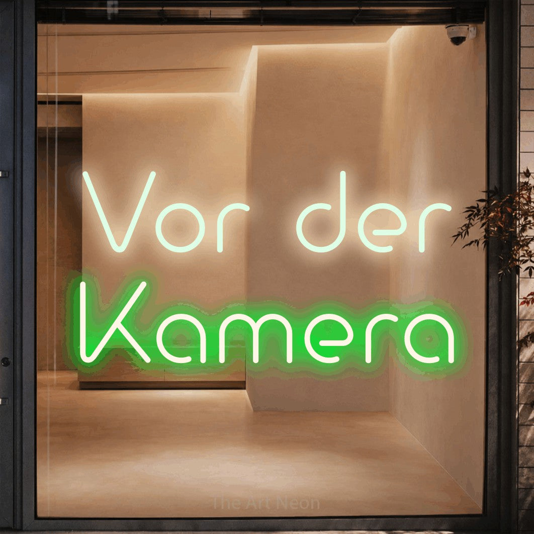 LED neon sign reading “Vor der Kamera”, arranged in 2 lines.