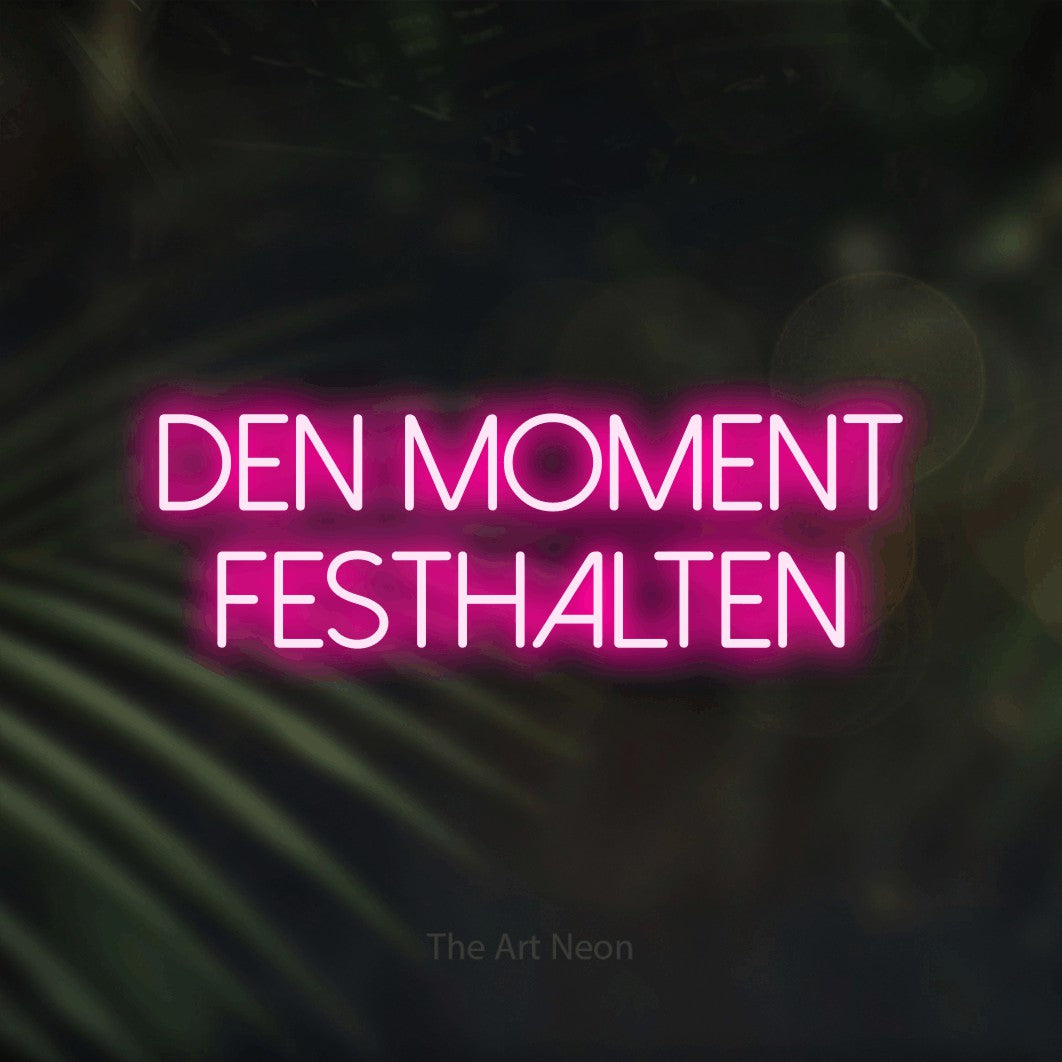 LED neon sign reading “Den Moment festhalten”, arranged in 2 lines.