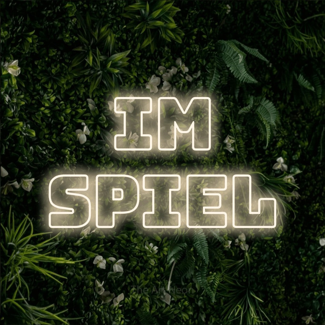 LED neon sign reading “im SPIEL”, arranged in 2 lines.