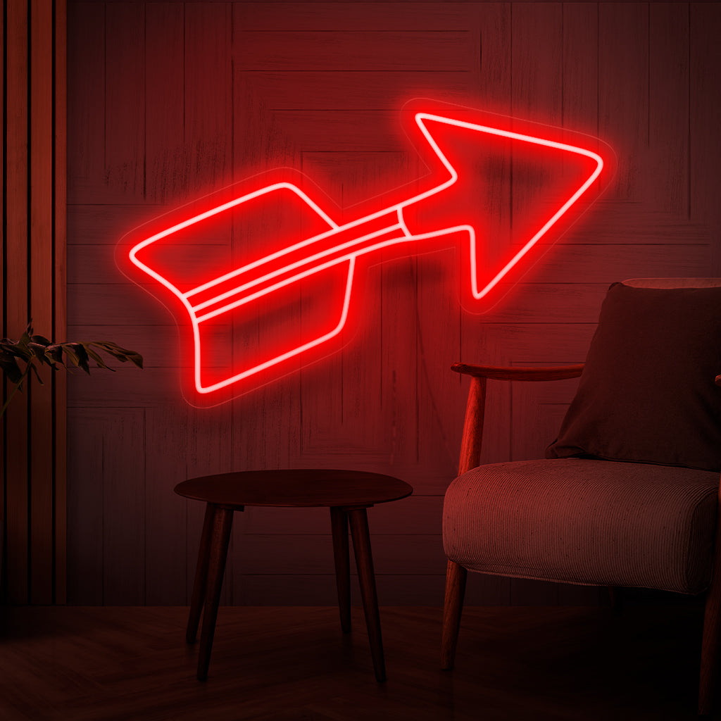 Ein beleuchtetes Neonschild mit einem leuchtend roten Pfeil, der die Richtung symbolisiert und auf ein stilvolles und dekoratives Element zeigt, das jedem Raum einen fesselnden Blickfang verleiht.