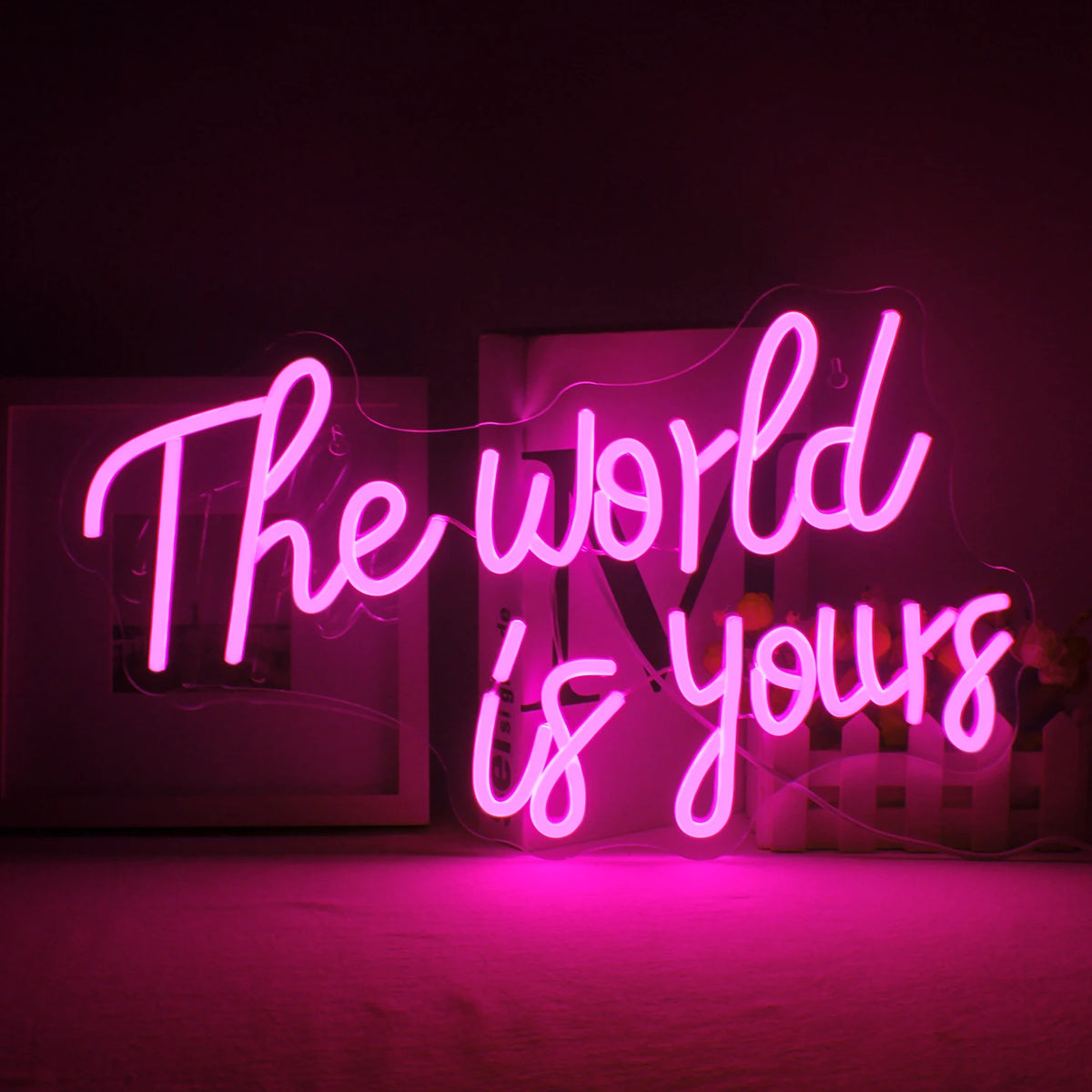Ein leuchtendes LED-Neonschild mit den Worten „The World Is Yours“ in einer stilvollen, kursiven Schriftart.