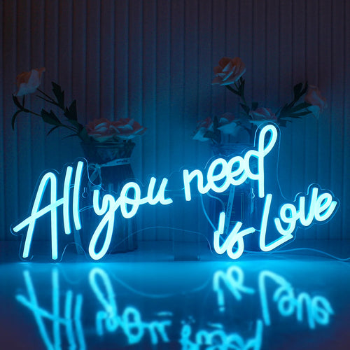 Das Bild zeigt ein leuchtendes LED-Neonschild mit dem Satz „All You Need Is Love“ in einer stilvollen Schreibschrift.