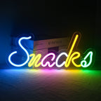 Das Bild zeigt ein farbenfrohes, handgefertigtes LED-Neonschild mit der Aufschrift „Colorful Snacks“.