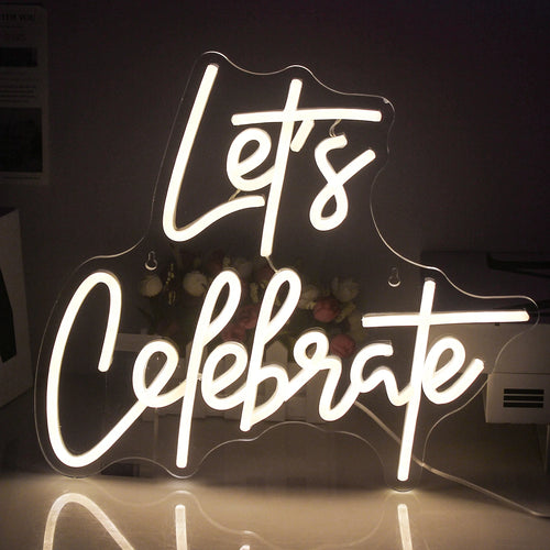 Das Bild zeigt ein leuchtendes LED-Neonschild mit der Aufschrift „Let’s Celebrate“.