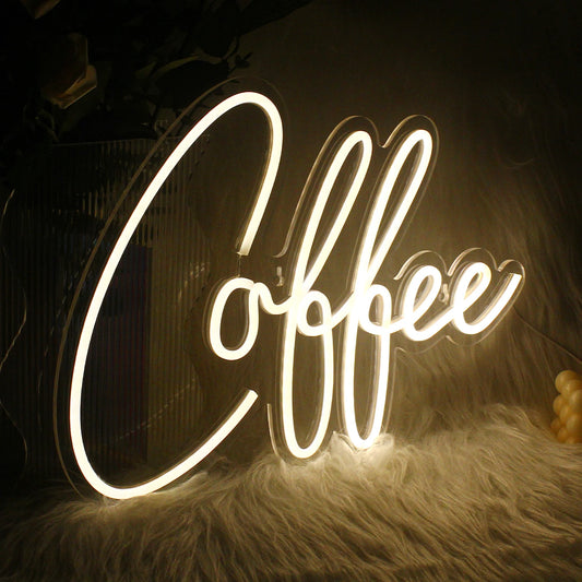 A vibrant LED neon sign shaped like a steaming coffee cup, illuminating a warm amber glow.