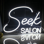 Das Bild zeigt ein leuchtendes LED-Neonschild mit dem Wort „SALON“ in stilisierten Großbuchstaben.