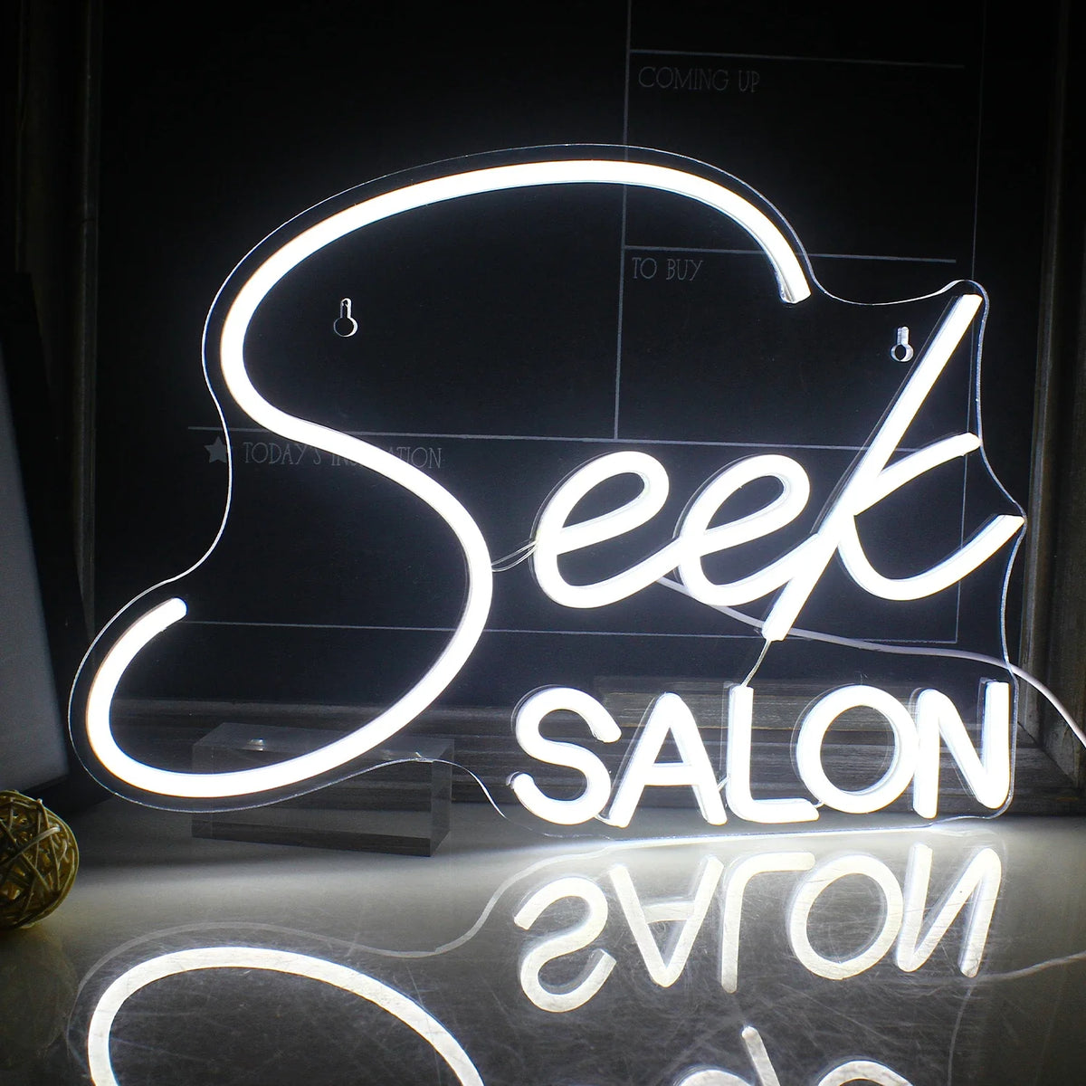 Das Bild zeigt ein leuchtendes LED-Neonschild mit dem Wort „SALON“ in stilisierten Großbuchstaben.