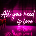 Das Bild zeigt ein leuchtendes LED-Neonschild mit dem Satz „All You Need is Love“ in eleganter, kursiver Schrift.