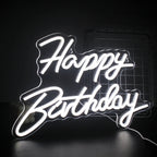 A vibrant "Happy Birthday" LED neon sign glowing warmly against a dark background.