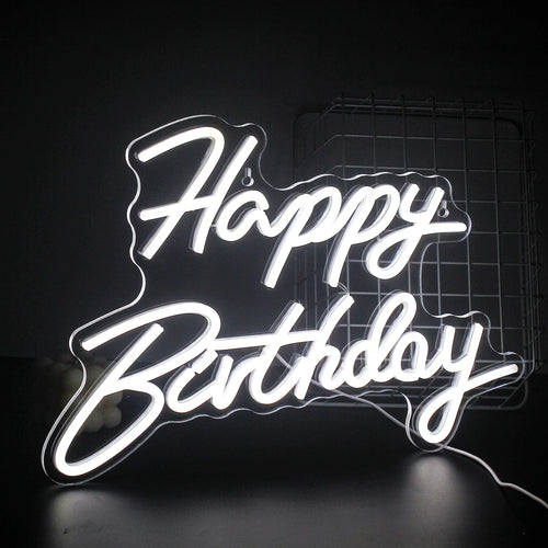 A vibrant "Happy Birthday" LED neon sign glowing warmly against a dark background.