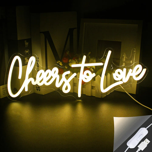 Das Bild zeigt ein lebendiges, handgefertigtes LED-Neonschild mit der Aufschrift „Cheers to Love“ in einer stilvollen Schreibschrift.