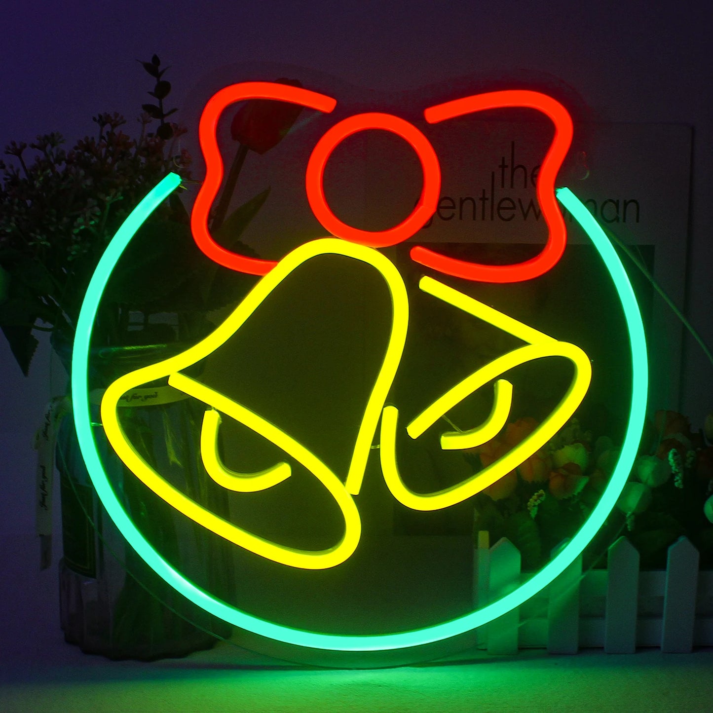 The image features a vibrant LED neon sign in the shape of a classic bell, often associated with Christmas festivities.