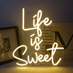 Das Bild zeigt ein lebendiges, handgefertigtes LED-Neonschild in hellen, leuchtenden Farben, auf dem der Satz „Life is Sweet“ steht.