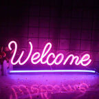 Ein leuchtendes LED-Neonschild mit der Aufschrift „Willkommen“ vor einer schlichten weißen Wand.