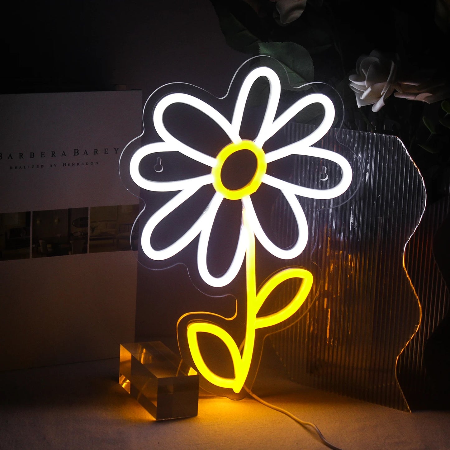 Das Bild zeigt ein buntes LED-Neonschild in Form einer niedlichen Cartoon-Gänseblümchenblume.