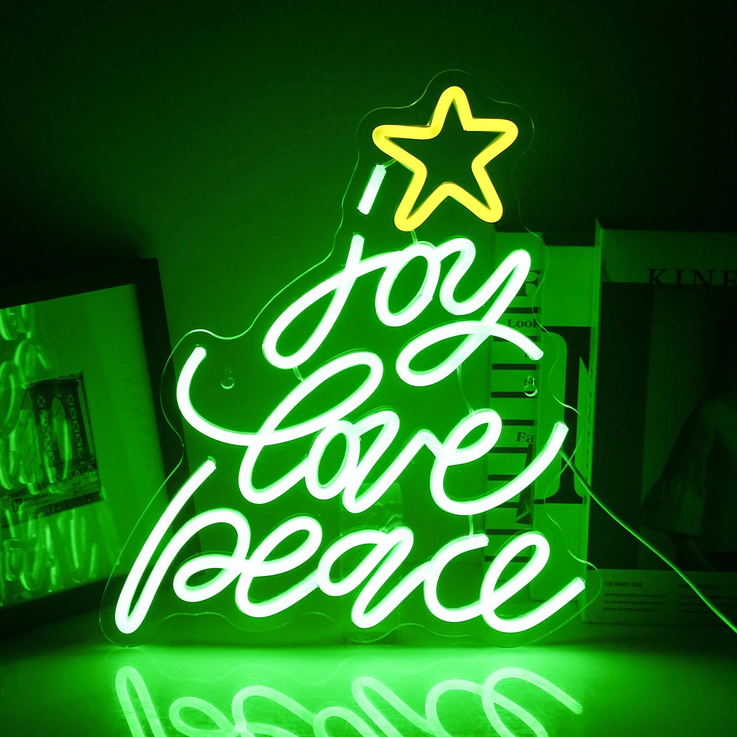 A vibrant LED neon sign shaped like a classic Christmas tree is displayed against a dark background.