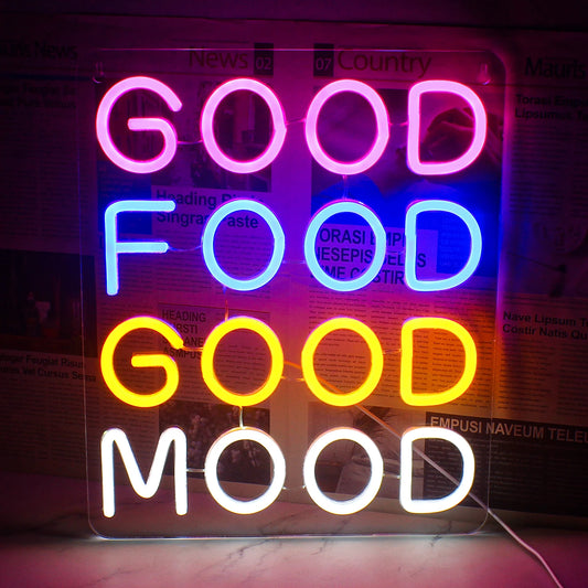 A vibrant LED neon sign displaying the words "Good Food Good Mood" in a playful, cursive font.