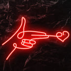 The image displays a vibrant LED neon sign in the shape of a "finger heart" gesture.