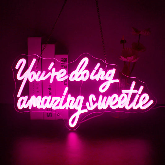 A vibrant LED neon sign displaying the phrase "You're Doing Amazing Sweetie" in elegant, cursive handwriting.