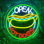 The image features a brightly lit LED neon sign displaying the words "Open Hot Dogs" in a playful, retro font.