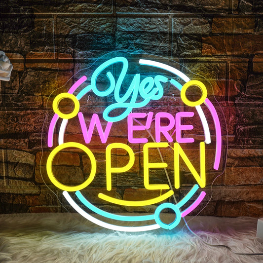 The image shows a vibrant LED neon sign displaying the message "Yes We are Open.