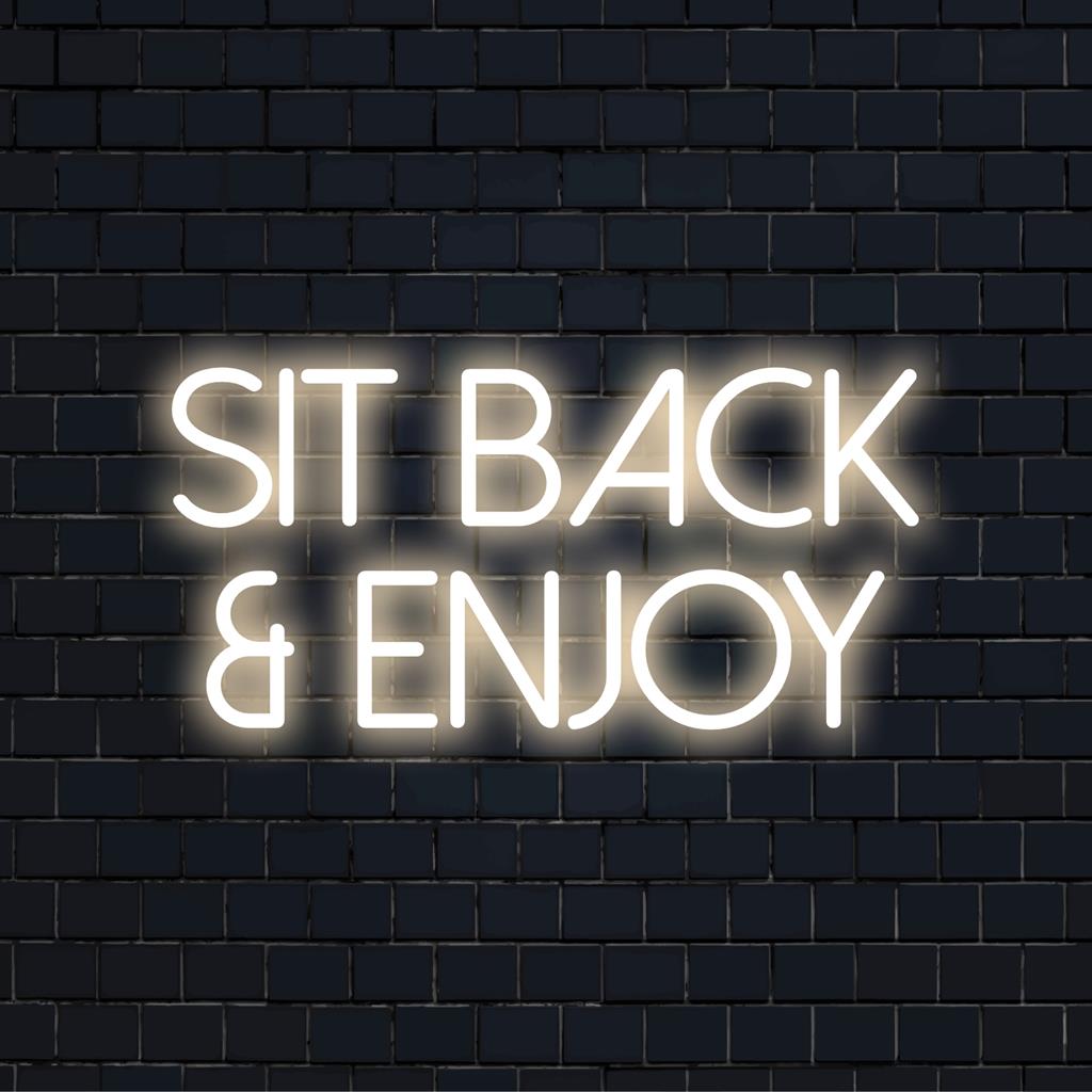 Custom LED neon sign reading Sit Back And Enjoy in bright hues, perfect for enhancing relaxation spaces and lounge areas.