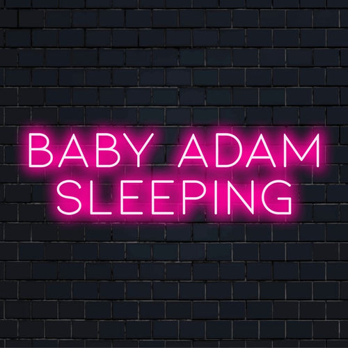 Baby Adam Sleeping Custom Name Neon Sign, glowing wall decor against brick backdrop