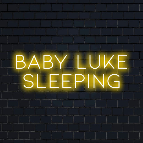 Baby Luke Sleeping Personalized Neon Light with bright neon lettering on dark brick wall