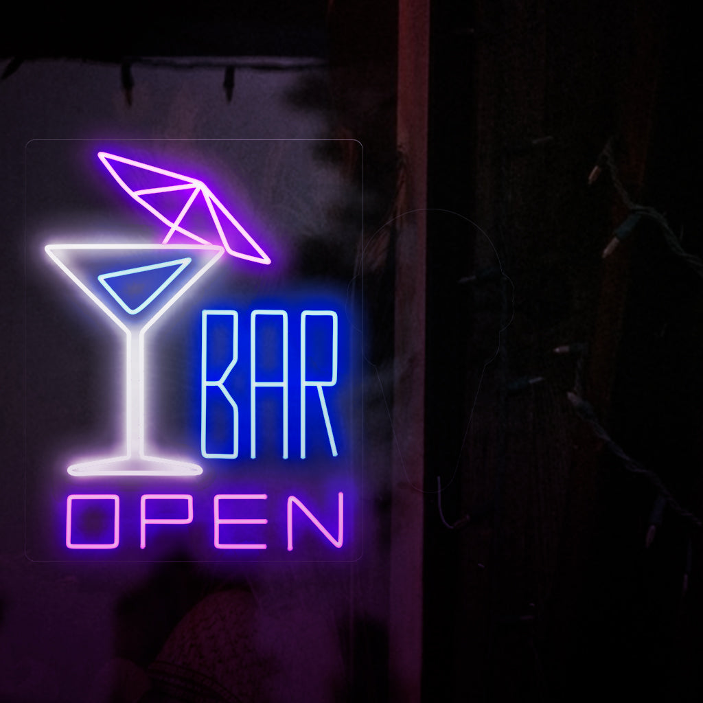Das Foto zeigt ein Neonschild mit einem Cocktail mit Schirmchen auf der linken Seite und dem Text „Open Bar“ auf der rechten Seite. Dieses Neonschild ist ideal für Bars im Innen- und Außenbereich.