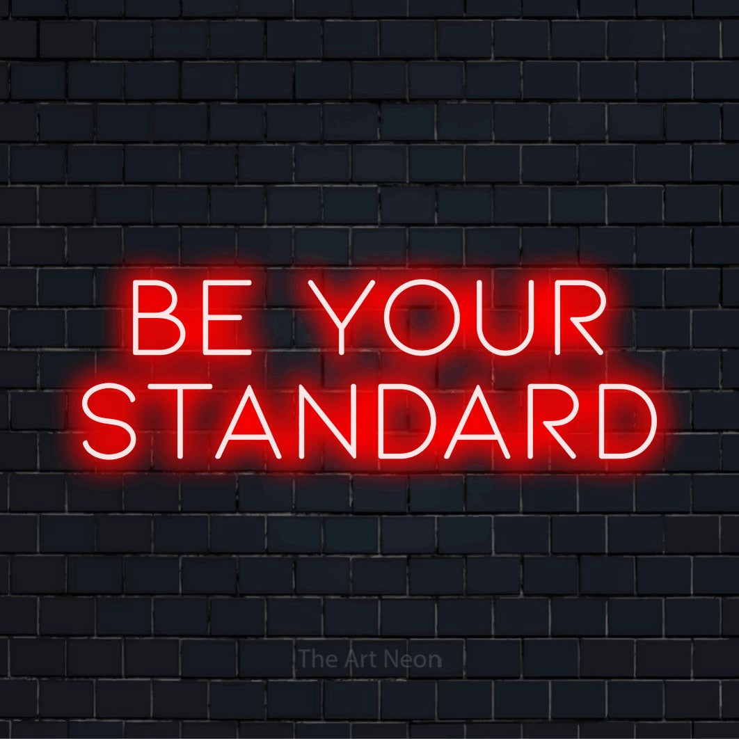 "Be Your Standard" neon text design on a black brick wall