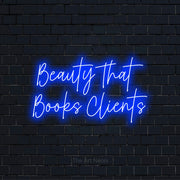 "Beauty That Books Clients" script-style LED neon sign on a black brick wall