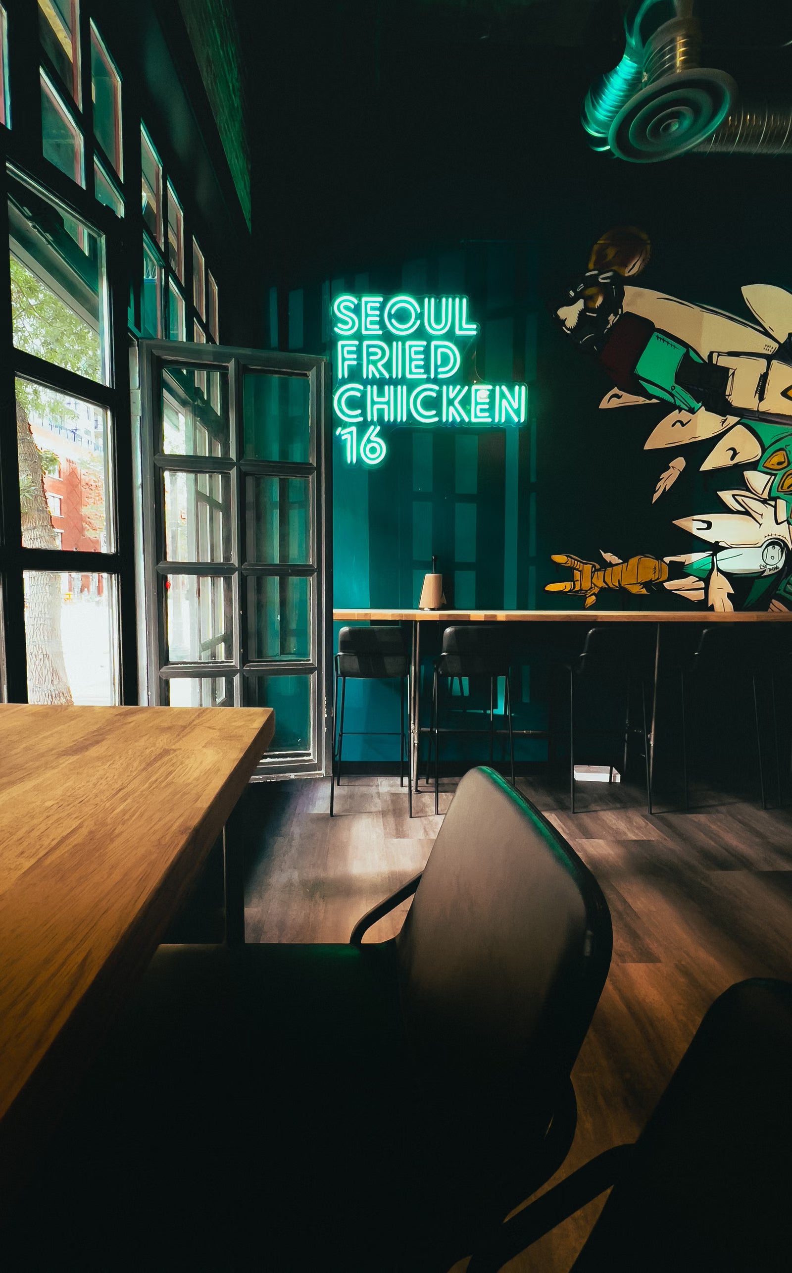 Grünes LED-Neonschild für ein Restaurant neben Esstischen und großen Fenstern