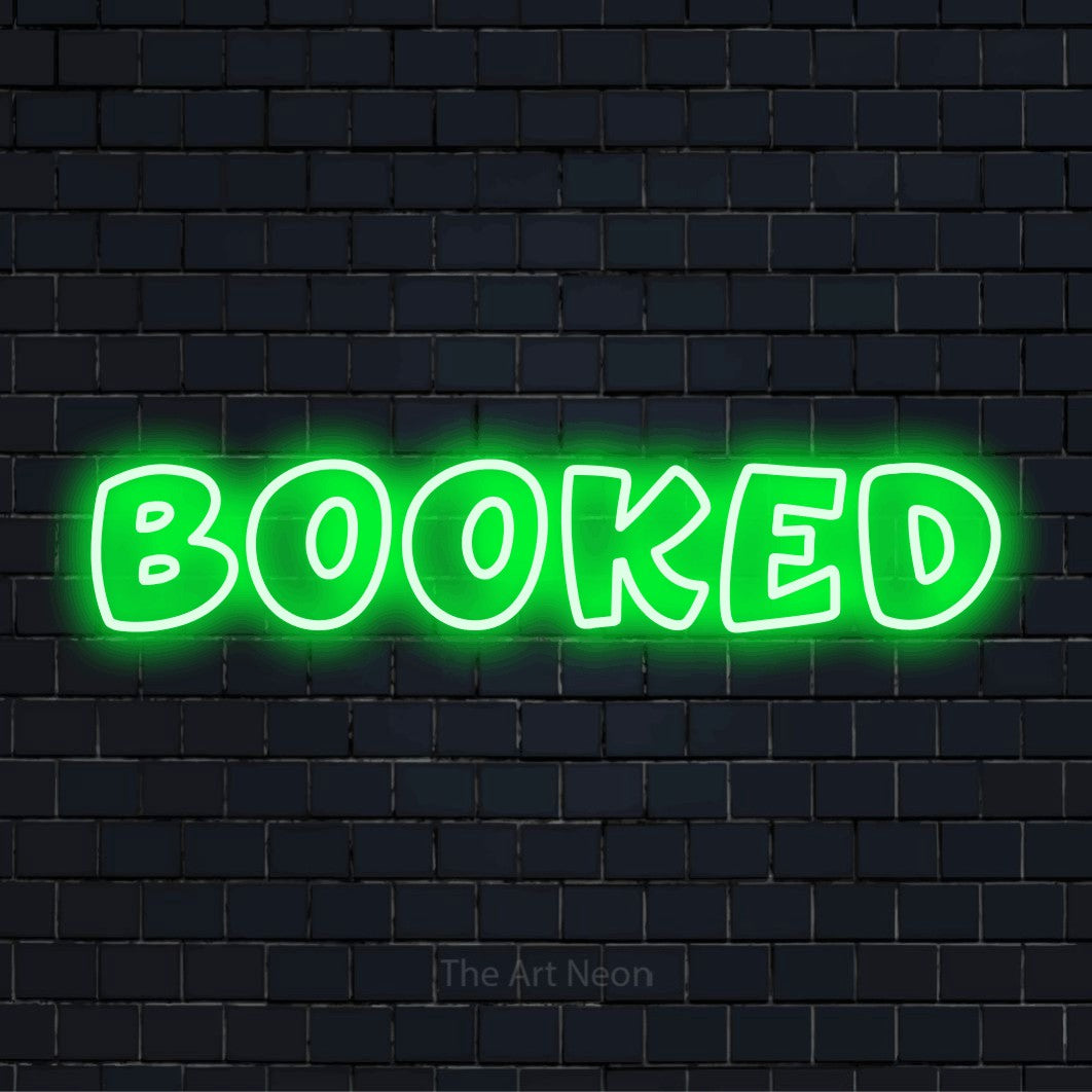 "Booked" script-style LED neon sign on a black brick wall