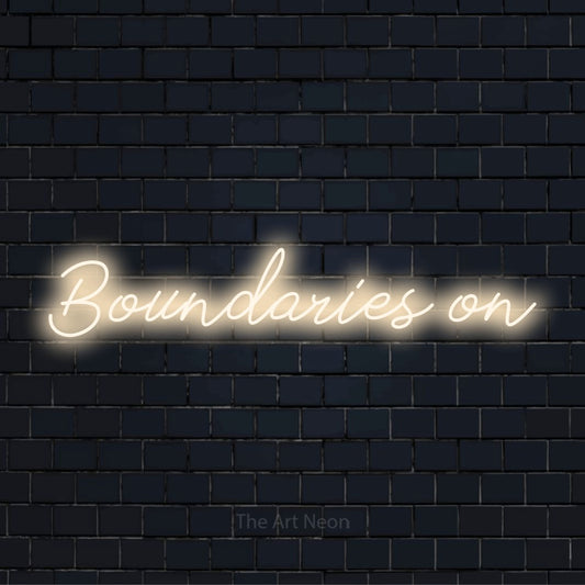 "Boundaries On" neon text design on a black brick wall