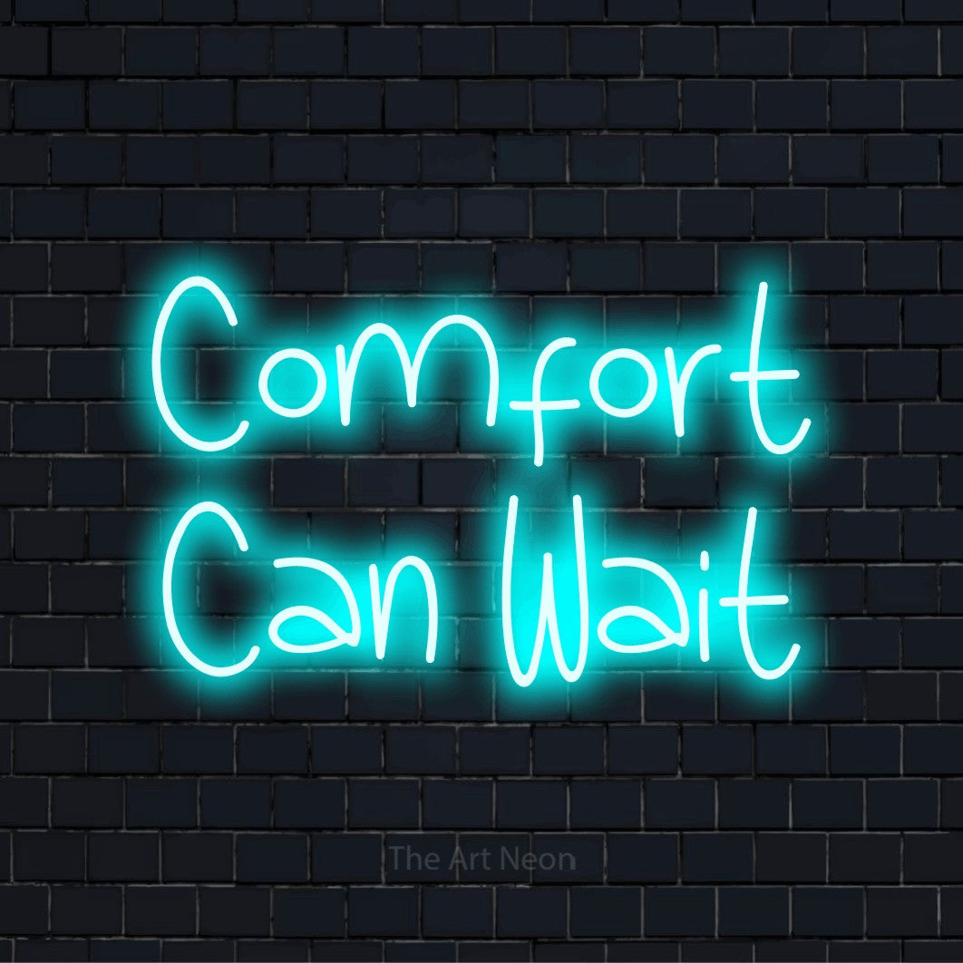 "Comfort Can Wait" text design with neon effect on a black brick wall