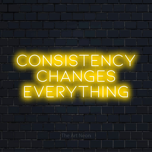 "Consistency Changes Everything" glowing LED neon sign on a black brick wall