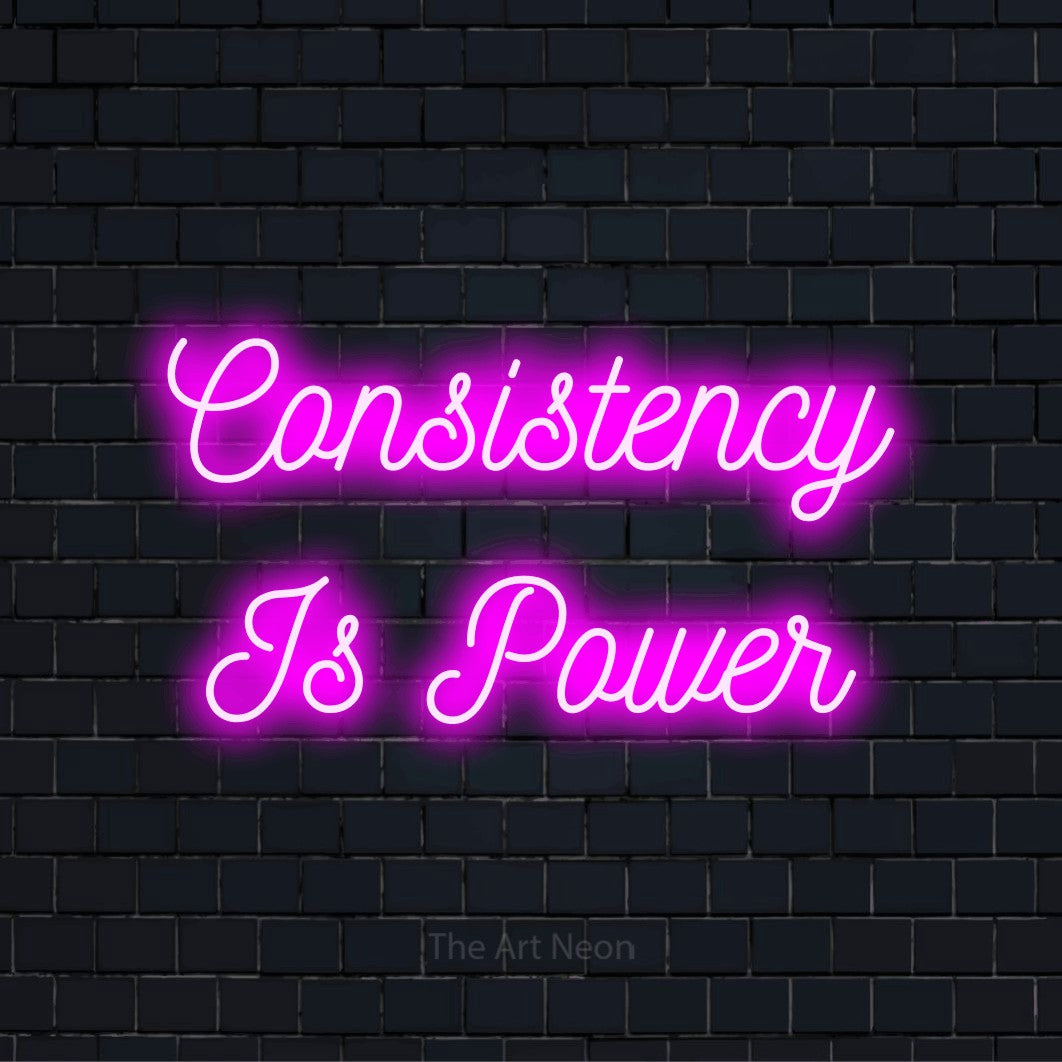 "Consistency Is Power" script-style LED neon sign on a black brick wall