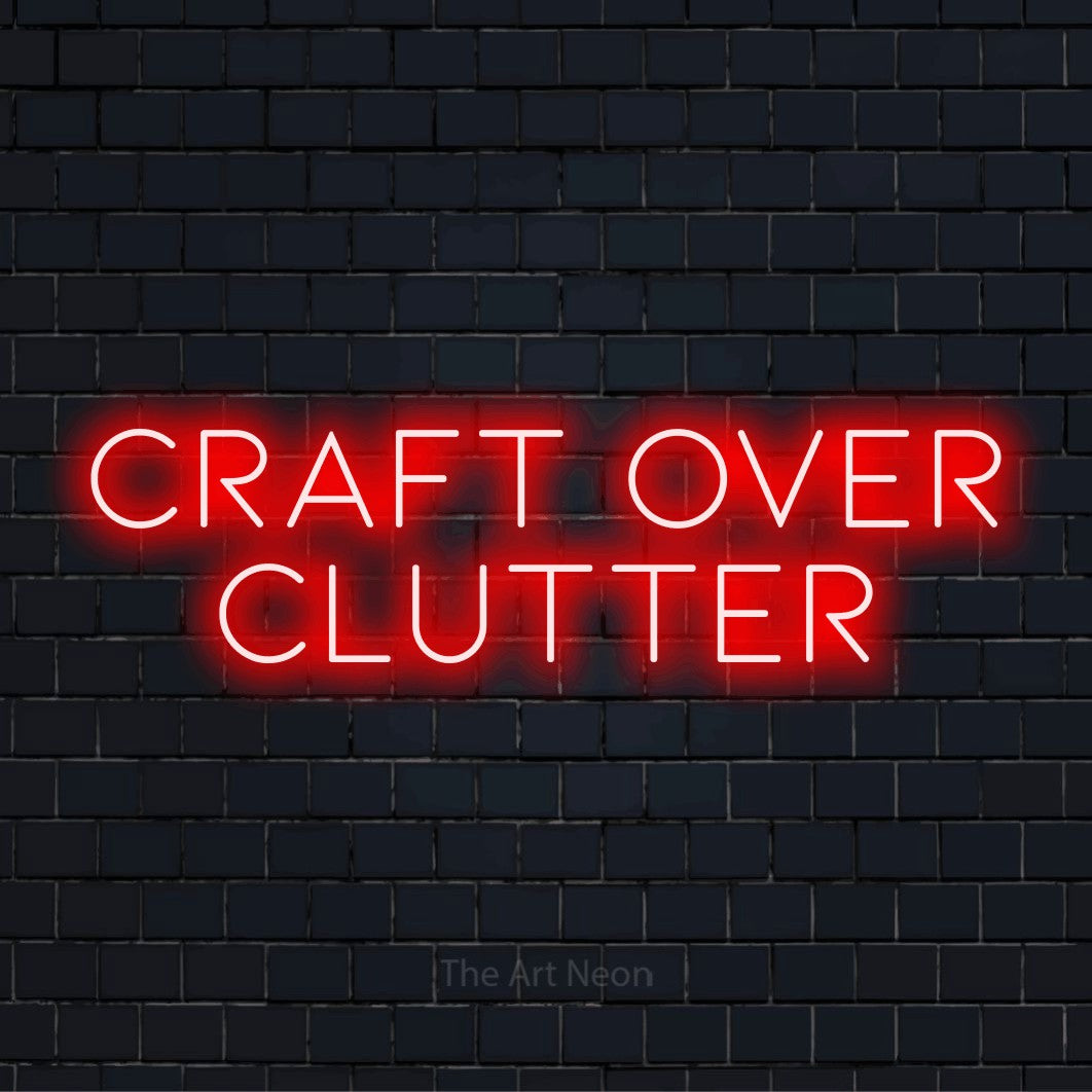"Craft Over Clutter" script-style LED neon sign on a black brick wall