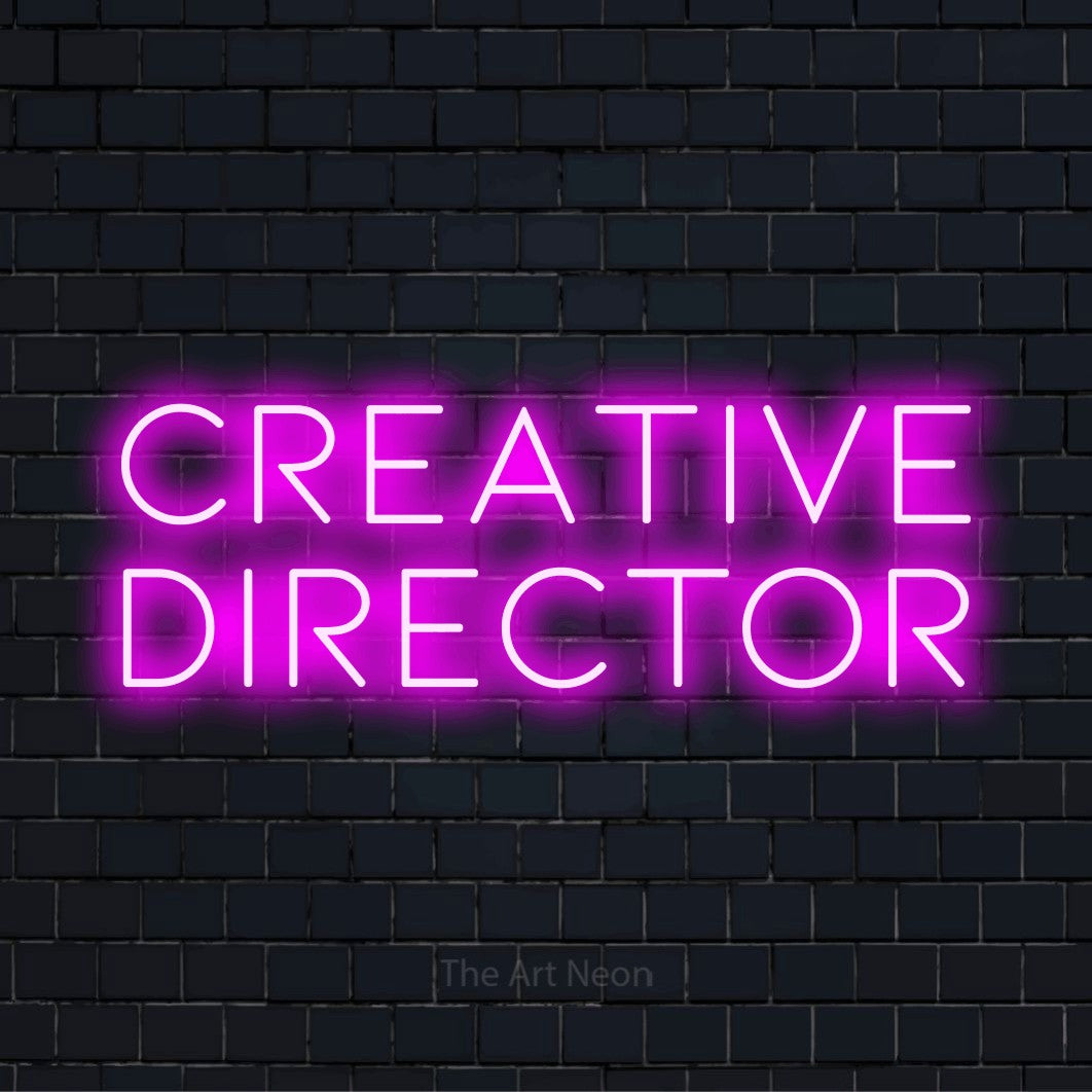 "Creative Director" script-style LED neon sign on a black brick wall