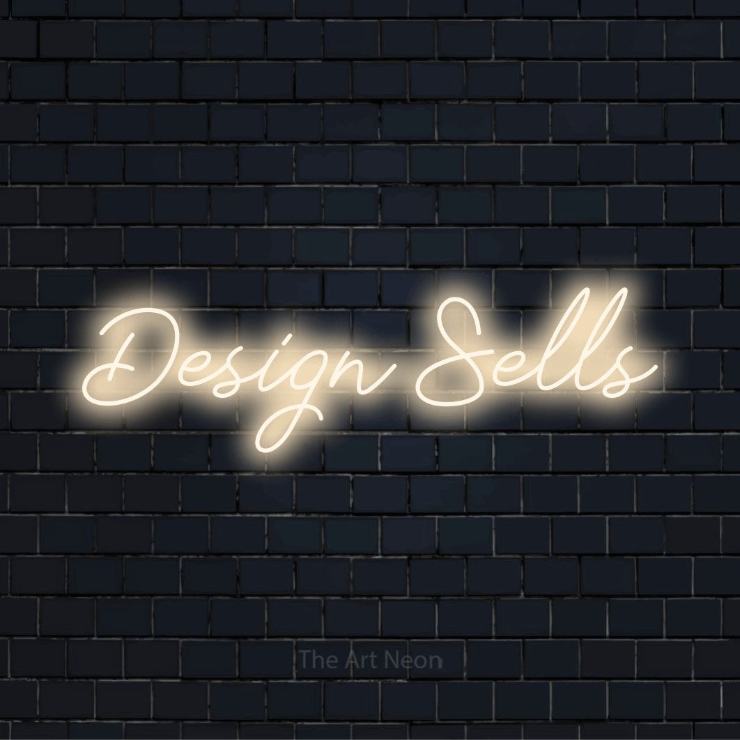"Design Sells" neon text design on a black brick wall